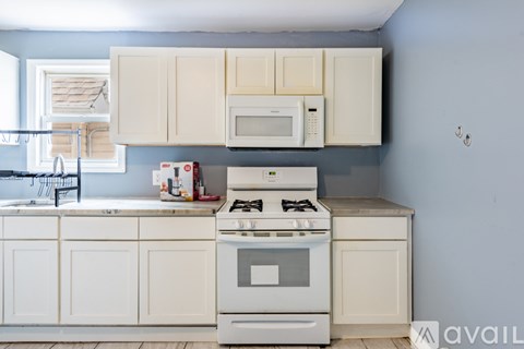 A kitchen with a white stove and cabinets.