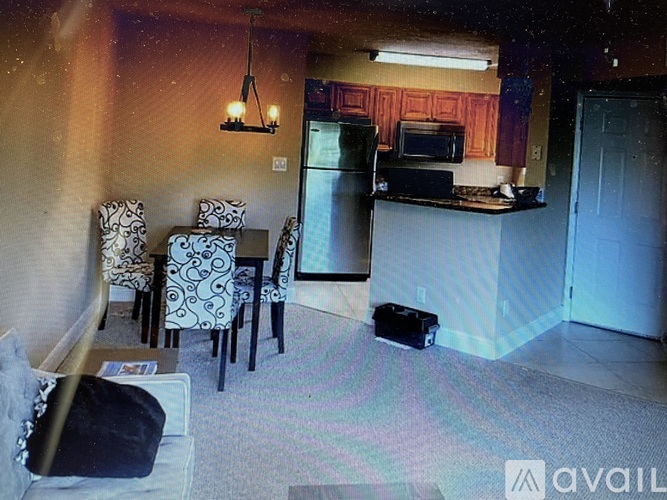A kitchen area with a refrigerator, microwave, and a dining table with chairs.