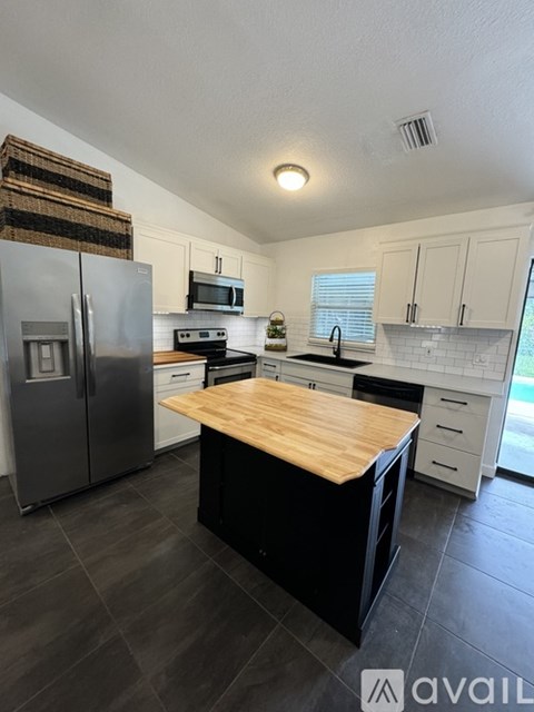 A kitchen with a wooden counter top and a refrigerator.