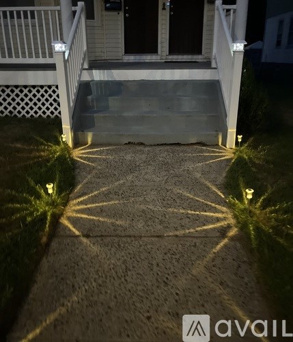 A set of stairs leading to a house entrance is illuminated by lights on the ground.