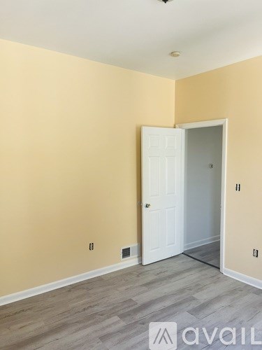A room with a white door and a wall with a light switch.