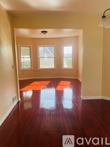 A room with wooden floors and three windows.