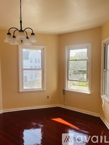 A room with a chandelier and two windows.