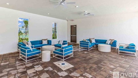 A living room with blue couches and a ceiling fan.