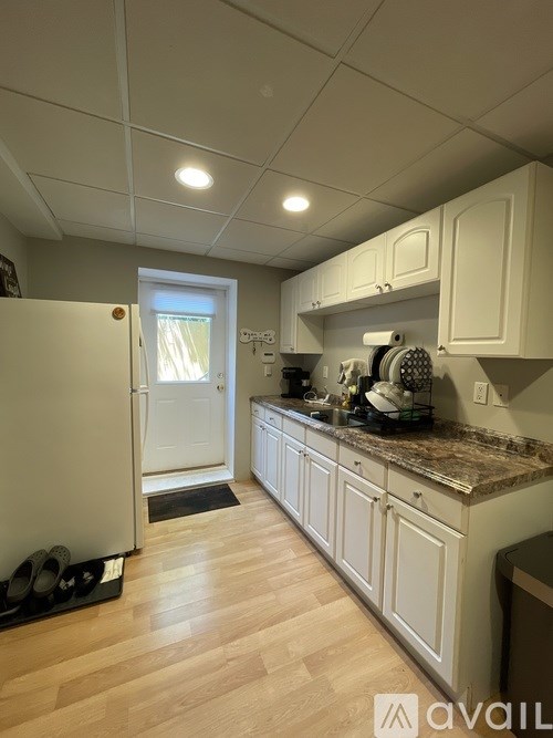 A kitchen with white cabinets and a white refrigerator.