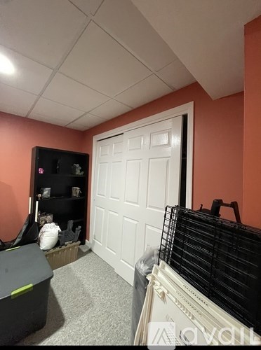 A room with a white door and a black shelf with various items on it.