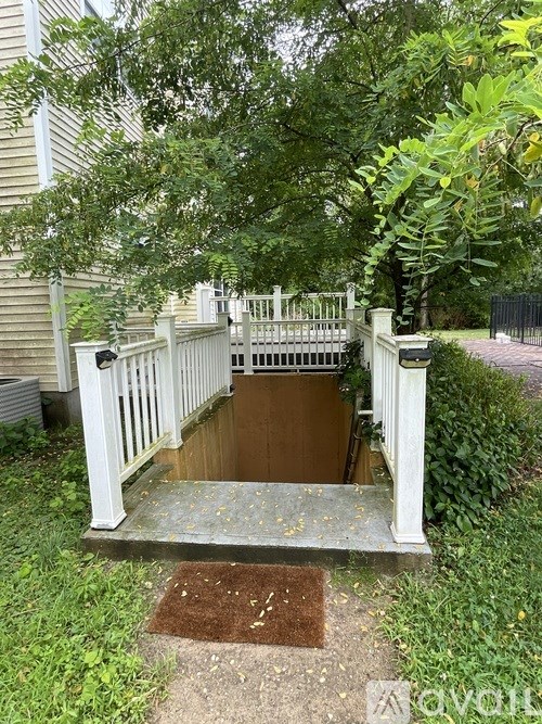 A white wooden staircase with a metal railing leads to a brown door.