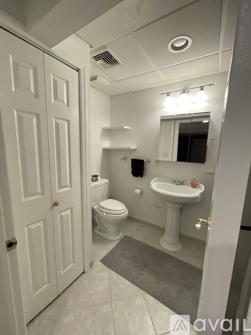 A bathroom with a toilet, sink, and mirror.