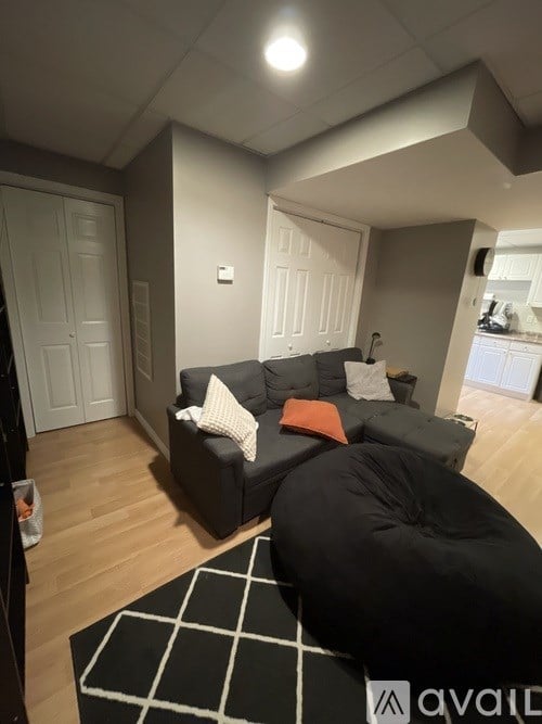A living room with a grey couch and a black bean bag chair.