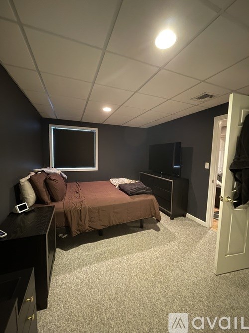 A bedroom with a bed, dresser, and television.