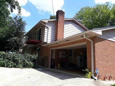 A house with a garage and a sign on the ground.