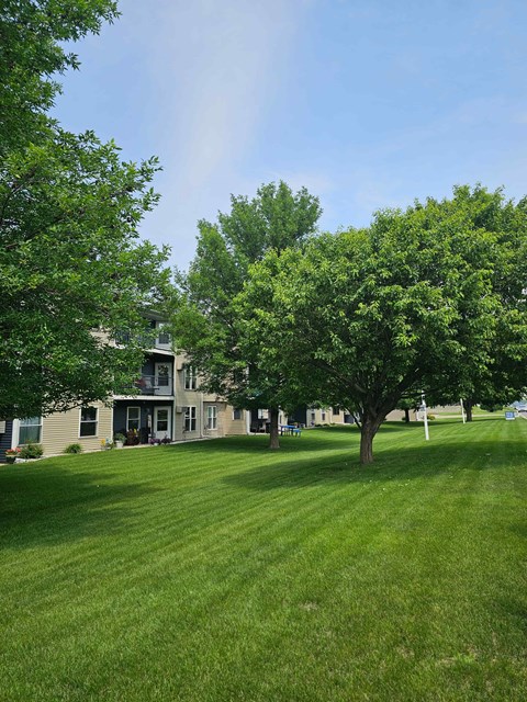 A house with a green lawn and trees in front of it.