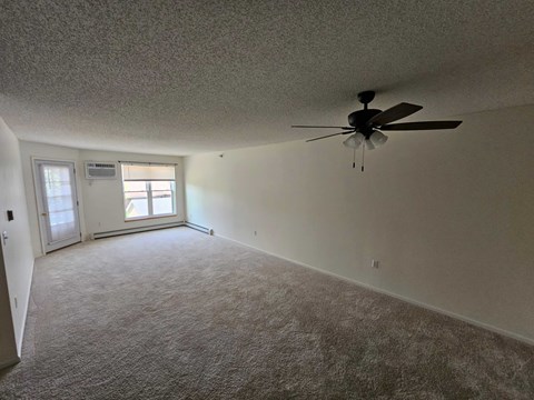 A room with a ceiling fan and carpeted floor.