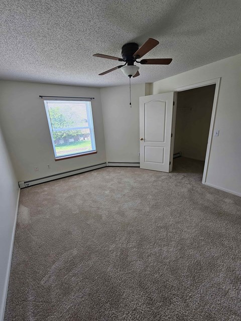 A room with a ceiling fan and a window.
