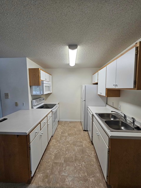 A kitchen with white appliances and brown cabinets.
