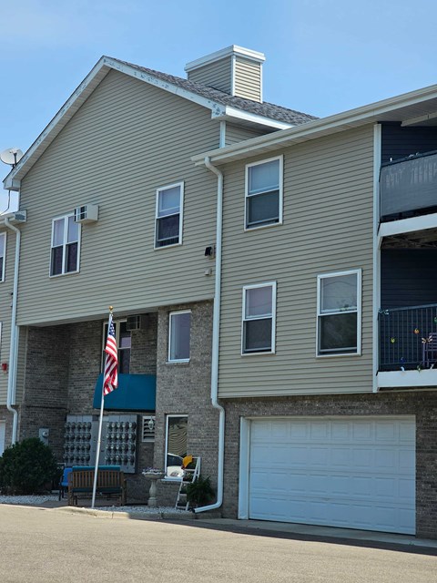A two-story building with a garage door and an American flag.