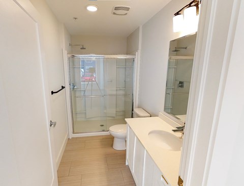 A white bathroom with a toilet, sink, and shower.