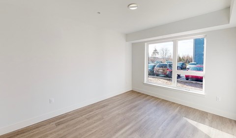 A room with a window showing a parking lot outside.