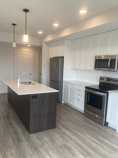 A modern kitchen with a white island and stainless steel appliances.