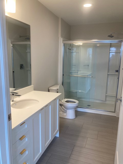 A white bathroom with a toilet, sink, and shower.