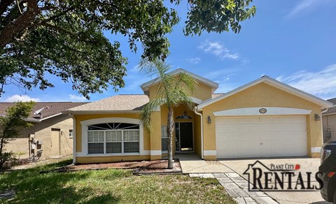 A yellow house with a sign that says "Plant City Rentals".