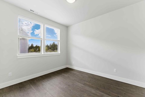 A room with a window showing a view of trees and a blue sky.