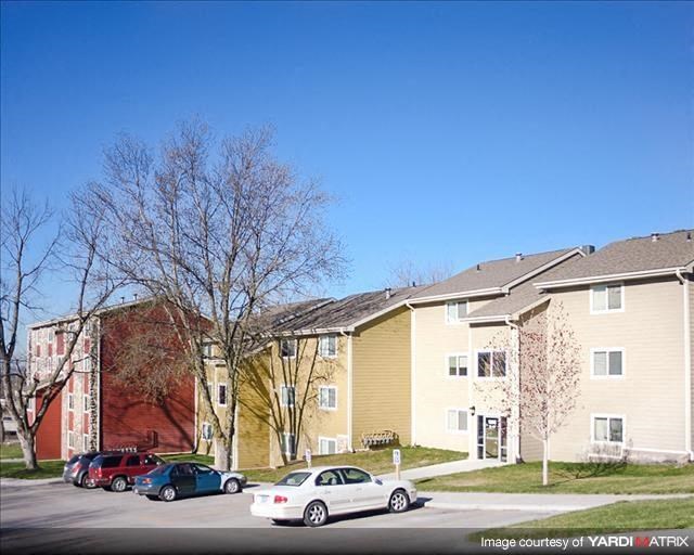 a row of apartment buildings with cars parked in front
