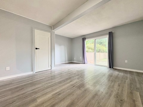 A room with a white door and a window with purple curtains.