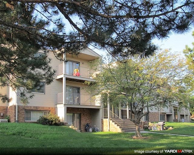 an apartment building with a yard and trees