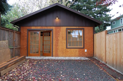 A small wooden house with a brown door and windows.