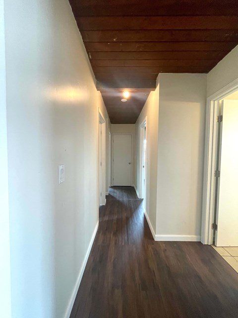 A long hallway with wood floors and white walls.