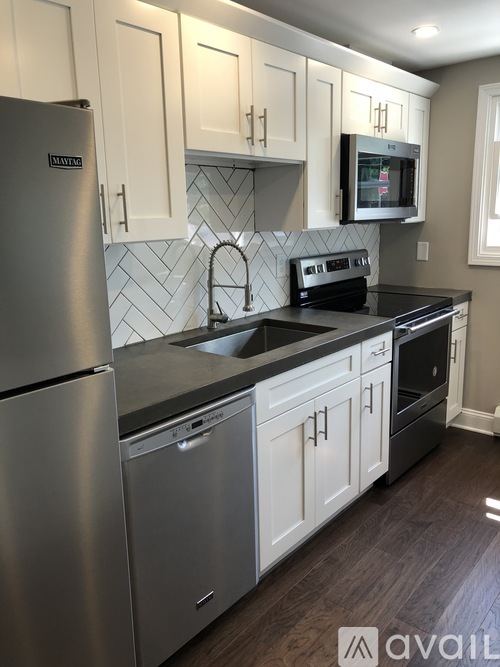 A kitchen with a stainless steel refrigerator and a black countertop.