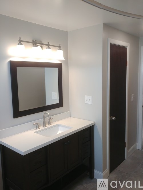 A bathroom with a sink, mirror and cabinet.