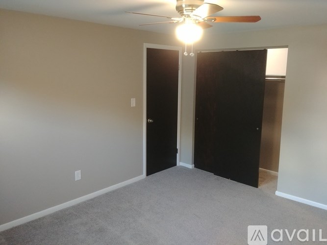 A room with a ceiling fan and two doors.
