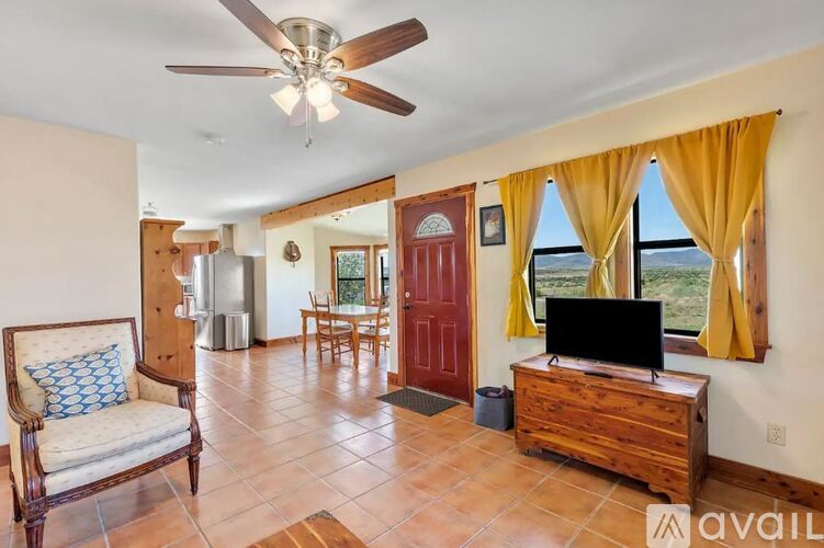A living room with a ceiling fan and a television on a wooden cabinet.