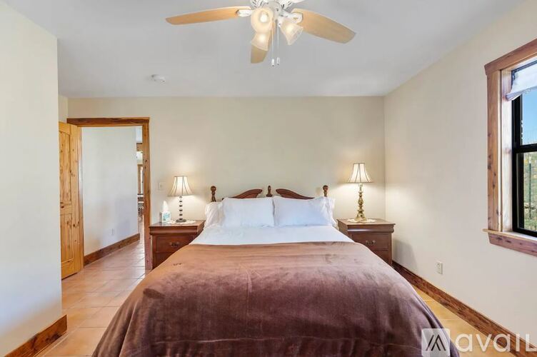 A bedroom with a large bed and a ceiling fan.
