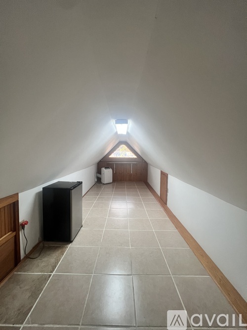 A hallway with a light at the end and a trash can.