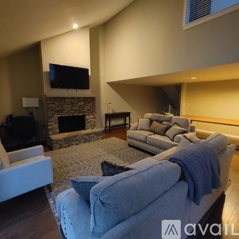 A living room with a grey couch and a stone fireplace.