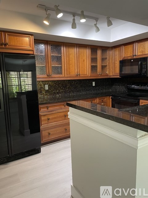 A kitchen with wooden cabinets and black appliances.