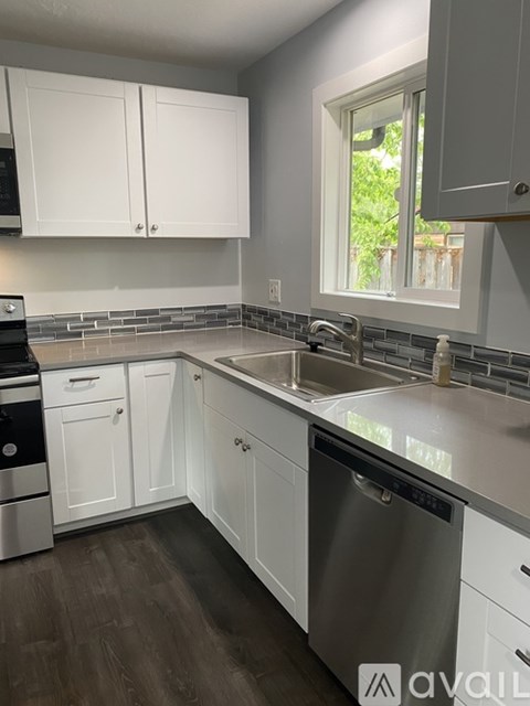 A kitchen with white cabinets and a stainless steel dishwasher.