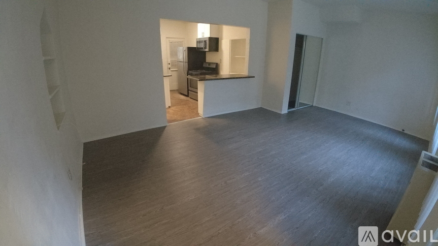 A room with wooden flooring and a television in the corner.