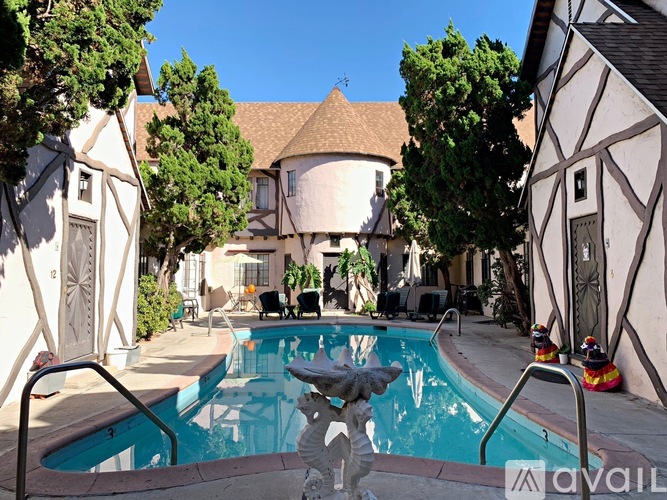 A swimming pool in a backyard surrounded by trees and a building with half-timbered walls.