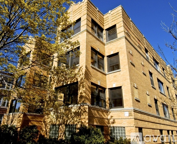 A tall building with many windows and a tree in front.