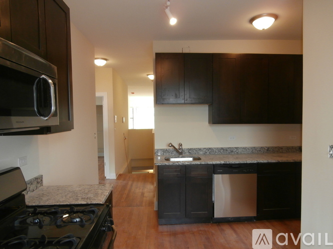 A kitchen with black cabinets and a granite countertop.