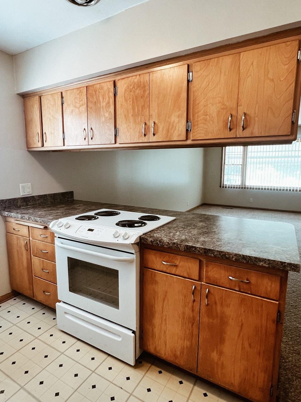 an empty kitchen with wooden cabinets and a white stove