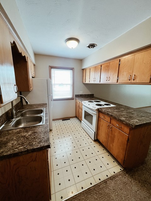 an empty kitchen with a sink stove and refrigerator