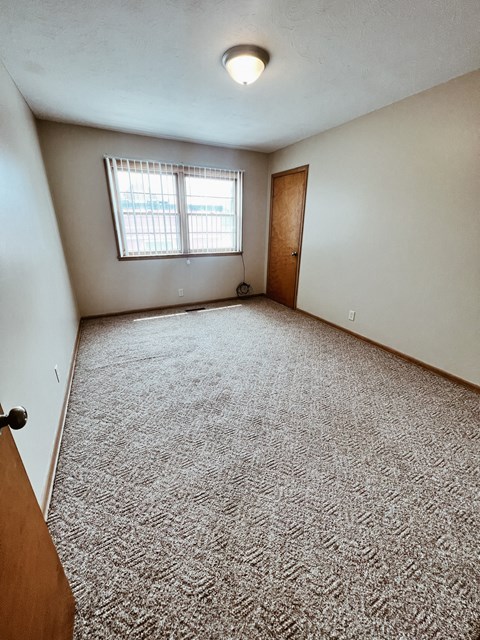 an empty room with carpet and a window