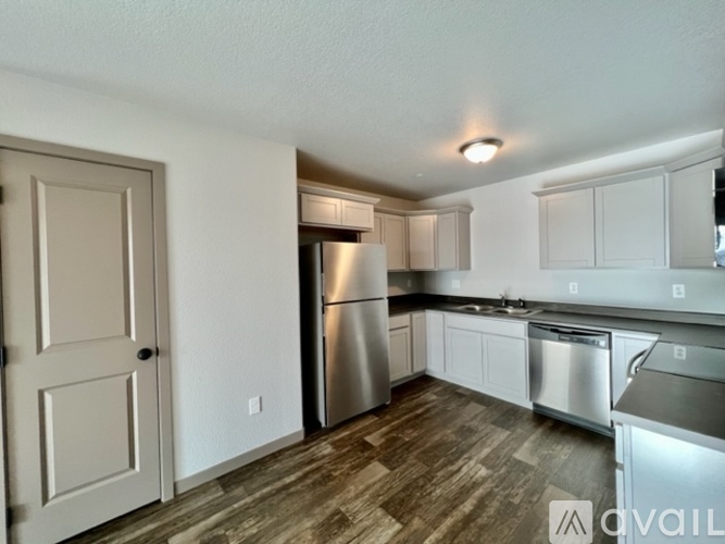 A kitchen with a refrigerator, sink, and cabinets.