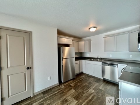 A kitchen with a refrigerator, sink, and cabinets.