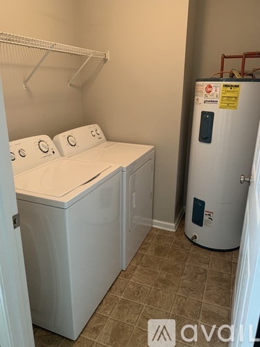 A small laundry room with a washer and dryer and a water heater.